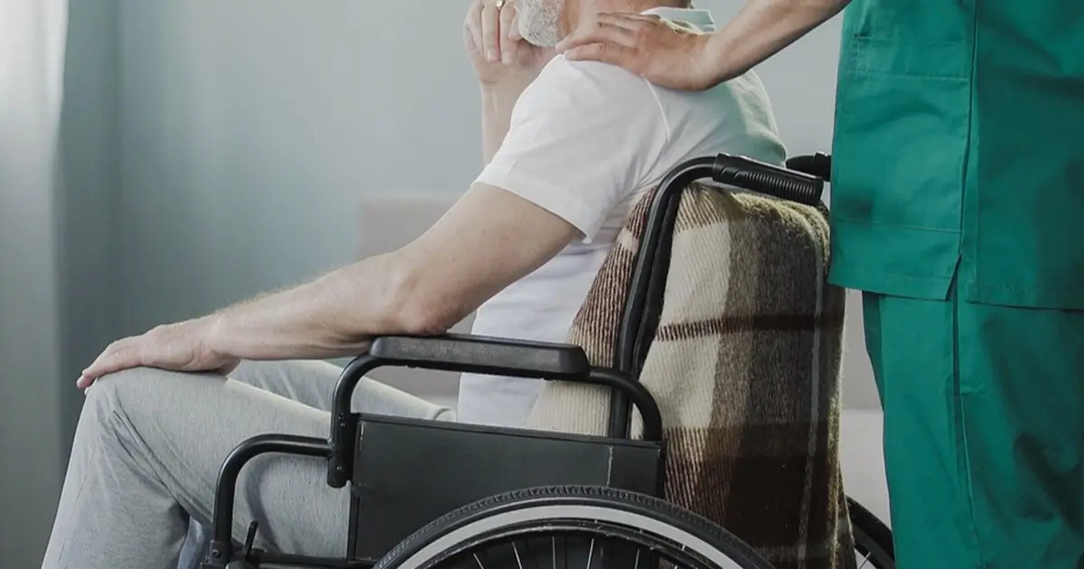 Patient in wheelchair being comforted by nurse