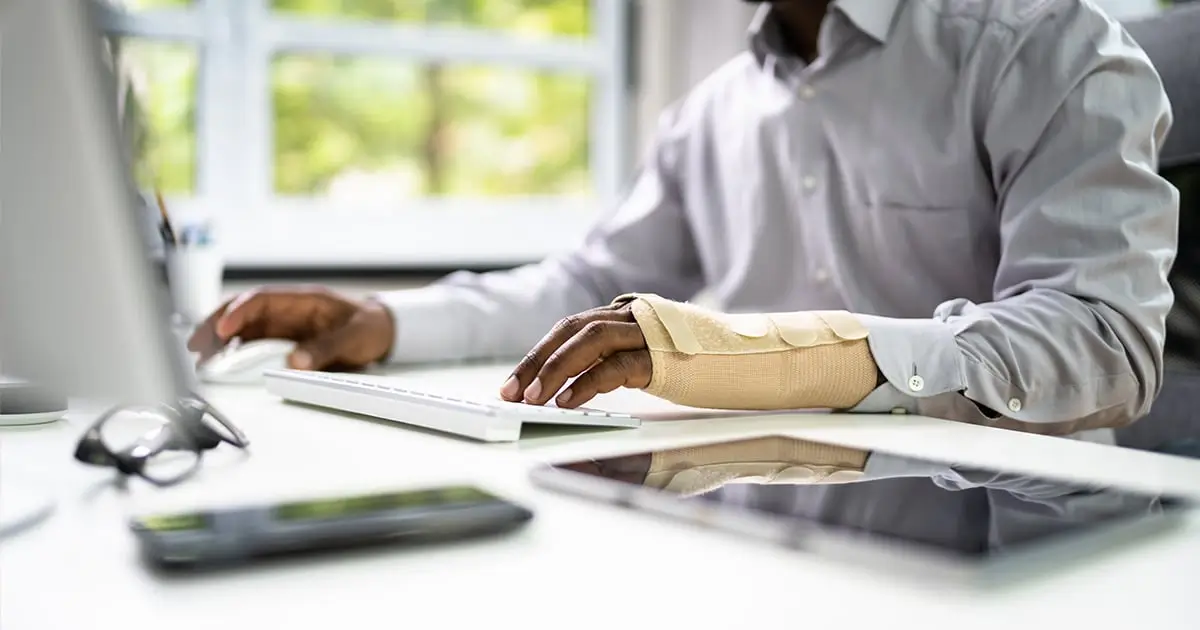man working on laptop with an arm cast