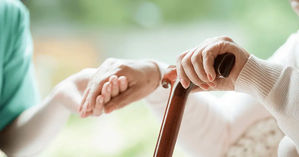 Nurse gently holding an elderly patient's hand to provide comfort and reassurance